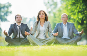 Business people exercising yoga in park.